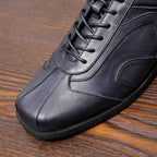 Men's dark gray leather sneaker close-up, lace eyelets and contrast stitching detail