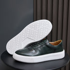 Leather sneakers showing white rubber outsole tread under dark green upper.