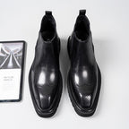 Black leather Chelsea dress boots with perforated toe detail and elastic side gore panels
