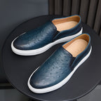 Men's blue slip-on leather sneakers with white soles and textured uppers, angled view