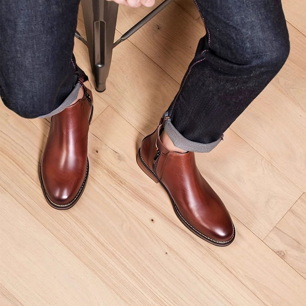 Dark brown leather pointed-toe dress boots with side zipper, worn over jeans.