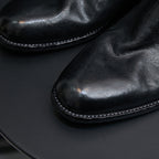 Black leather pointed-toe boot close-up with stitched edge trim