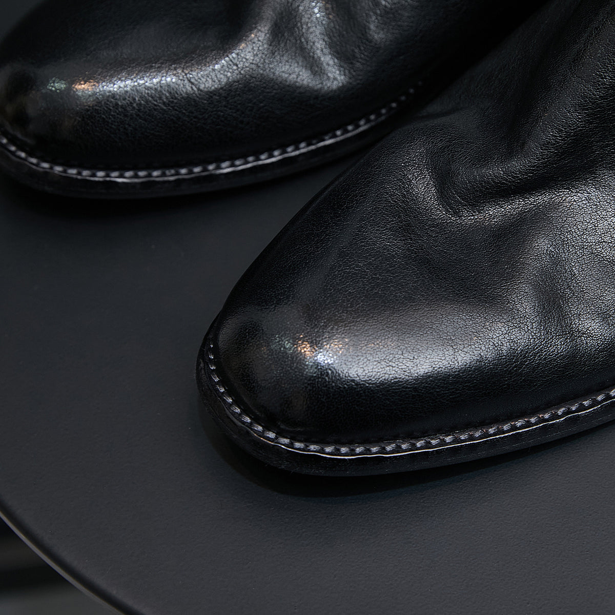 Black leather pointed-toe boot close-up with stitched edge trim