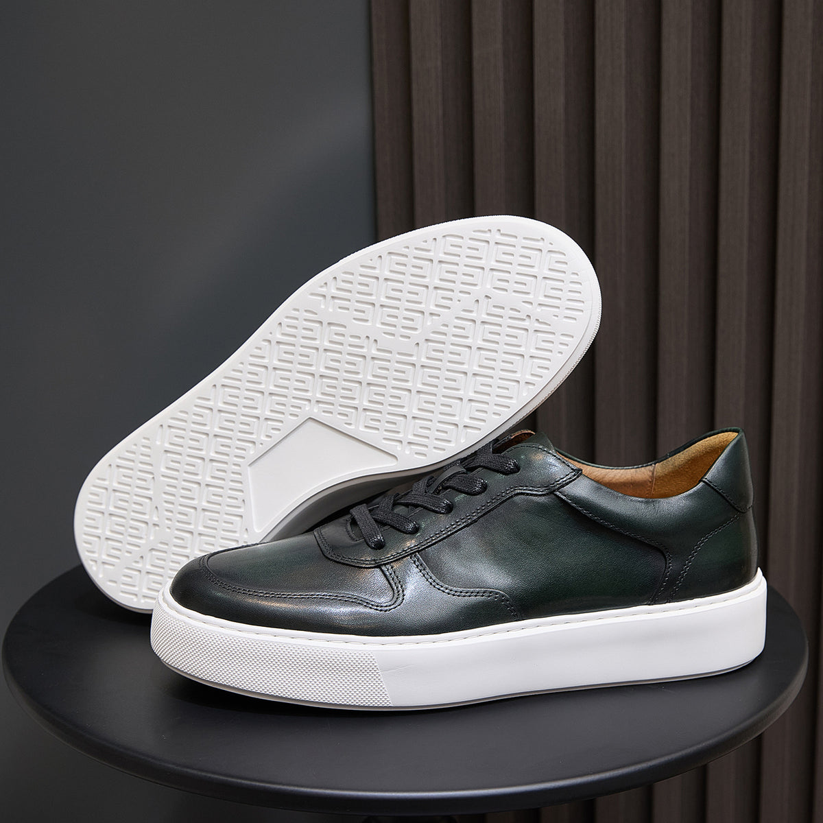 Men's dark green leather sneakers showing treaded white rubber outsole
