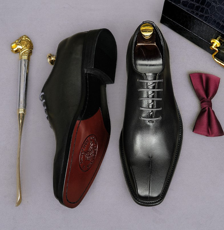 Men's black lace-up wingtip brogue oxfords, side view with outsole visible