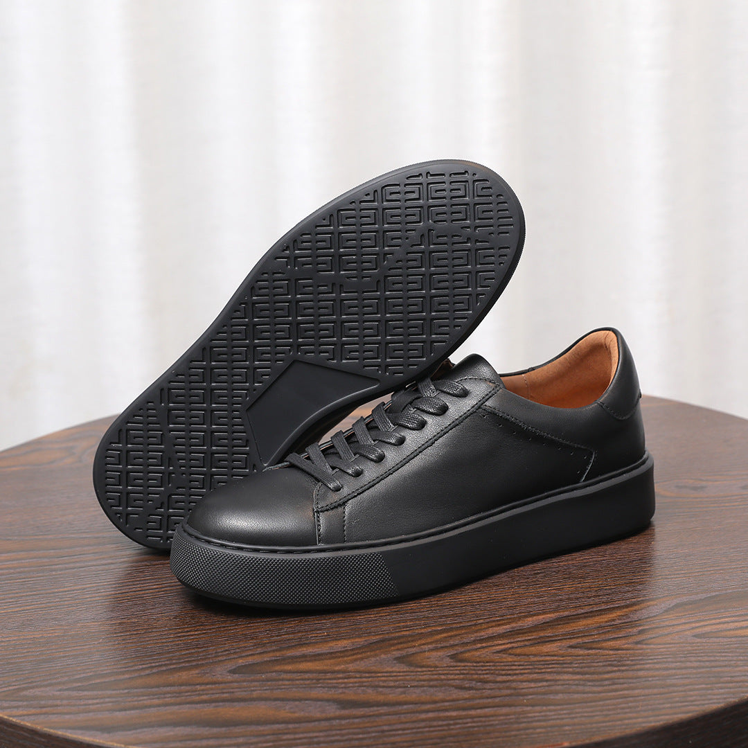 Men's black leather sneakers, outsole tread visible on a low rubber platform sole