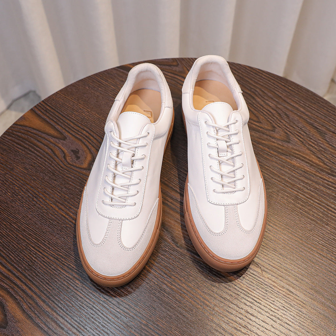 White leather sneakers close-up showing laces, toe shape, and tan trim