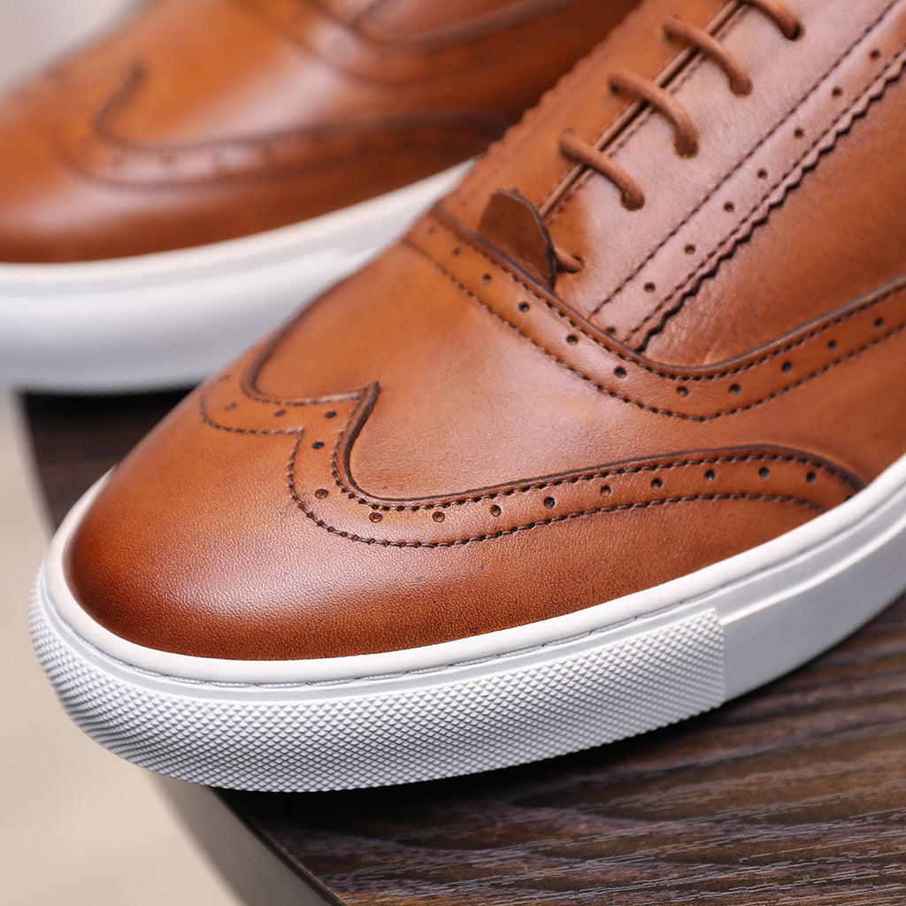 Close-up of men's brown leather sneaker toe with laces and white textured sole
