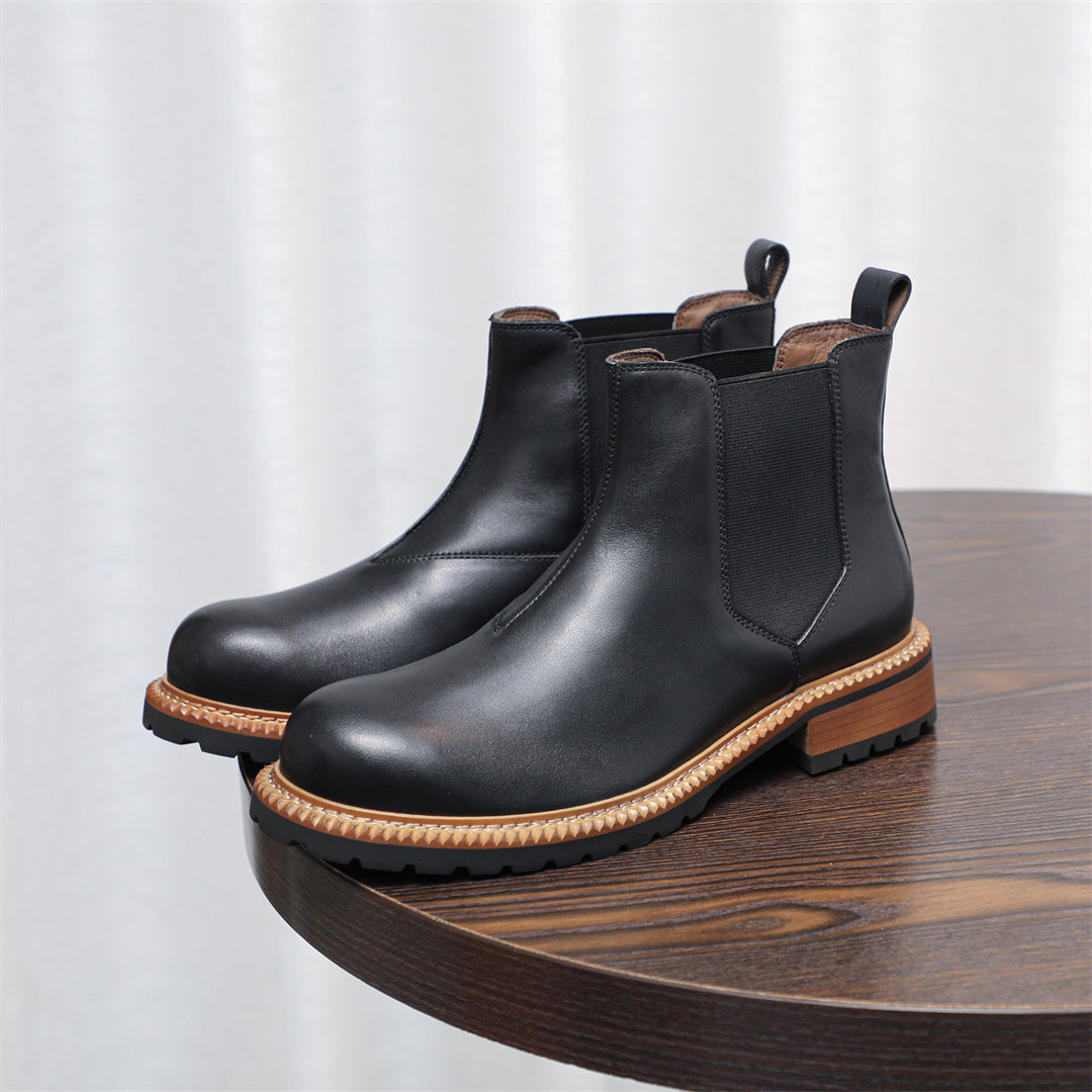 Black pointed-toe Chelsea boots with elastic side panels and tan welt trim, low heel
