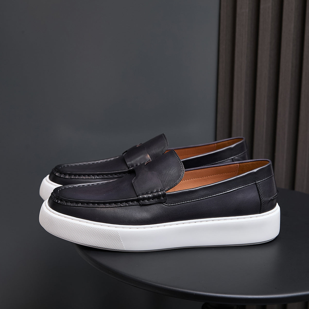 Black leather slip-on sneakers with strap detail and thick white rubber sole