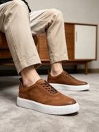 Brown leather sneakers with lace-up front and white sole, casual low top