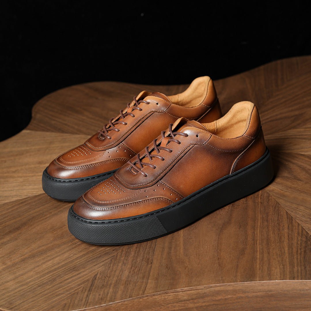 Brown leather lace-up sneakers with thick black sole, angled view on wooden floor.