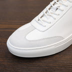 White leather sneaker toe and lace-up area with stitched detailing and textured sole edge