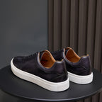 Men's leather sneakers, dark black with white sole and tan lining at the collar.
