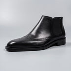 Black leather slip-on Chelsea dress boot with elastic side gore and perforated brogue detailing