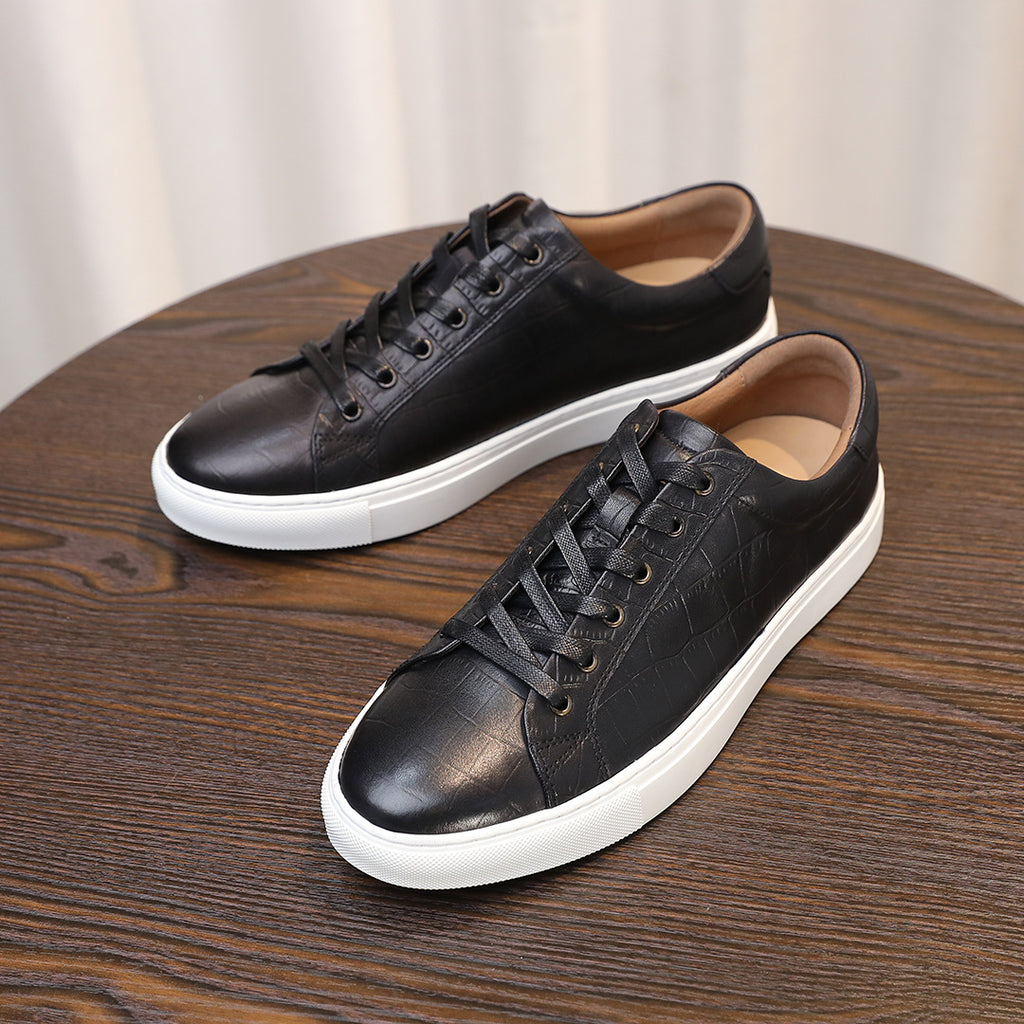 Black leather lace-up sneakers shown on a wooden surface