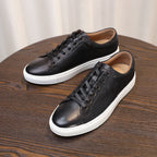 Black leather lace-up sneakers shown on a wooden surface