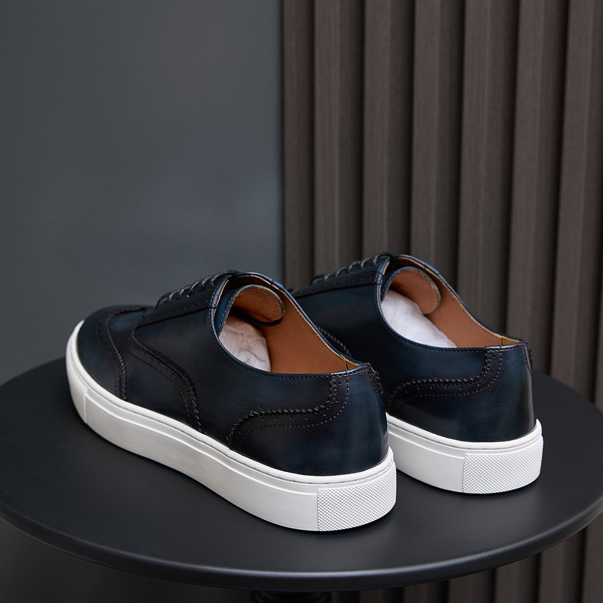 Dark blue leather sneakers from heel view with white rubber sole