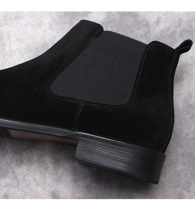 Black Chelsea boot close-up: elastic side panel and pull tab above textured sole