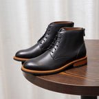 Black leather lace-up ankle boots with pointed toe and orange welt trim