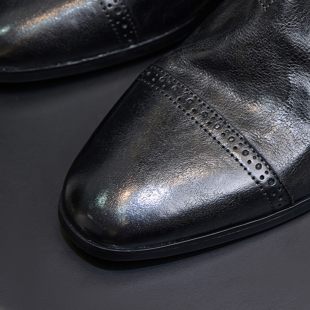Black Chelsea dress boot with wingtip-style perforated detailing on the toe