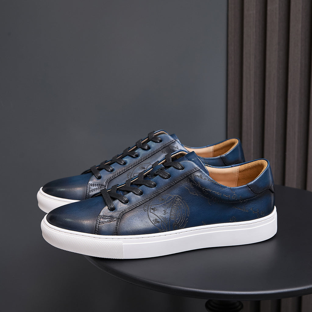 Pair of dark blue leather sneakers with black laces, embossed emblem, and white sole