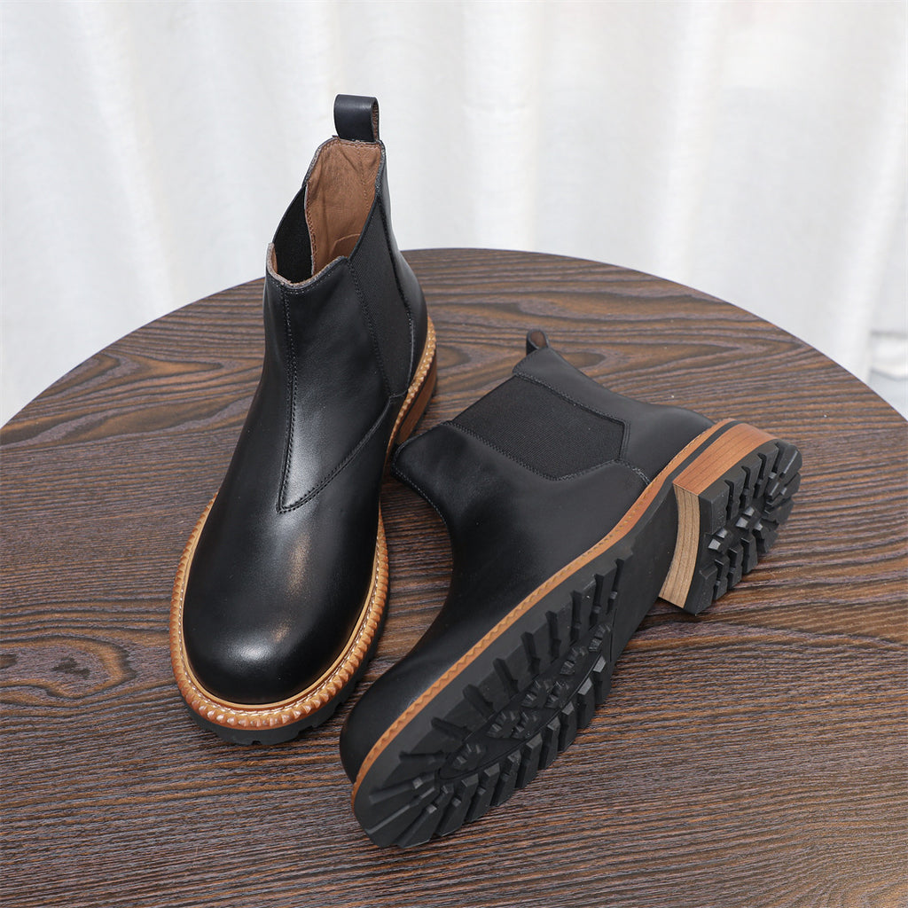 Black Chelsea boots with pointed toe and elastic gore, with outsole tread visible