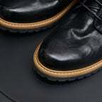 Black leather pointed-toe ankle boot with lace-up and side zipper detail.