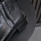 Black leather ankle boot detail with side zipper seam and stacked heel