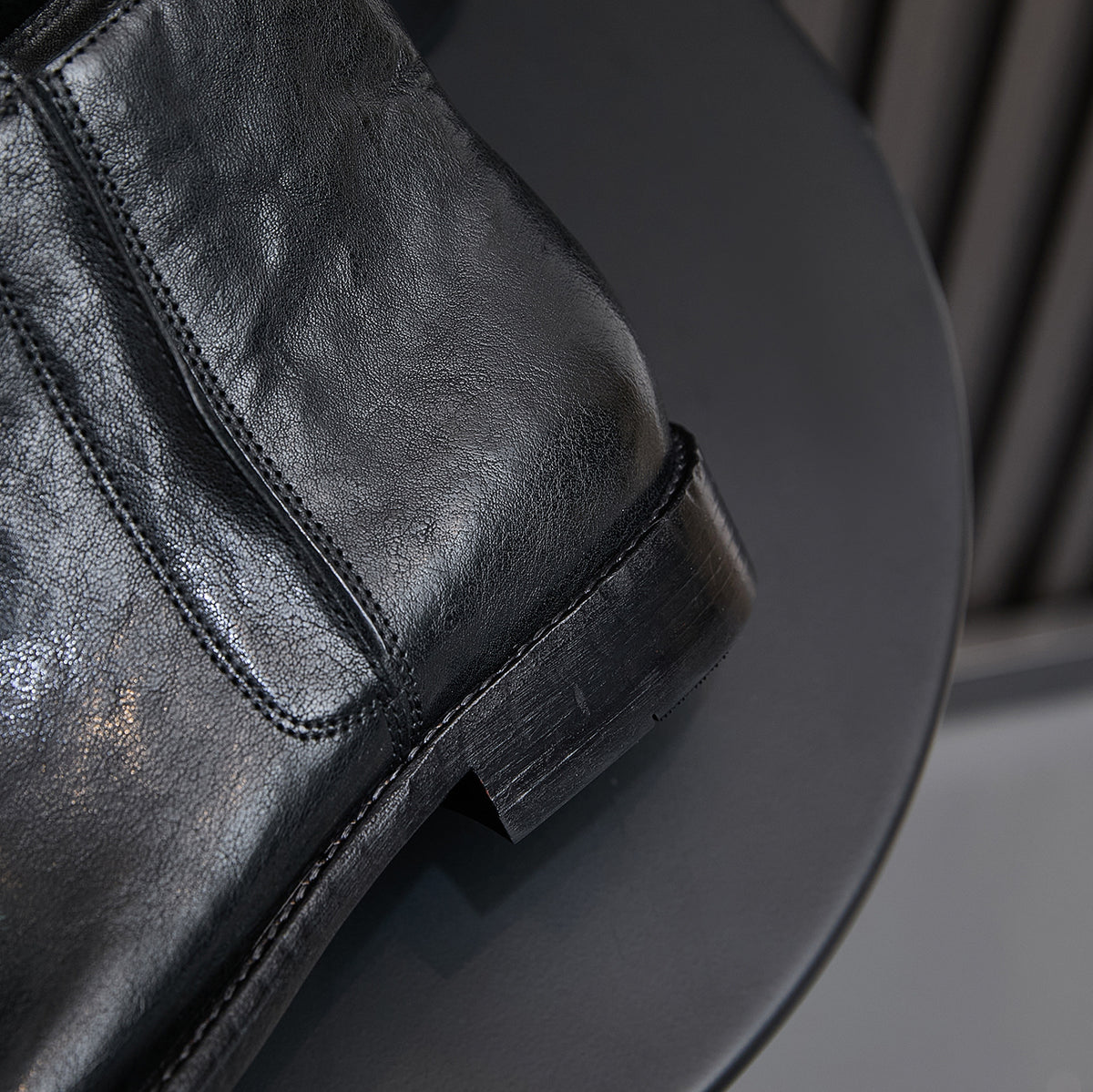 Black leather ankle boot detail with side zipper seam and stacked heel