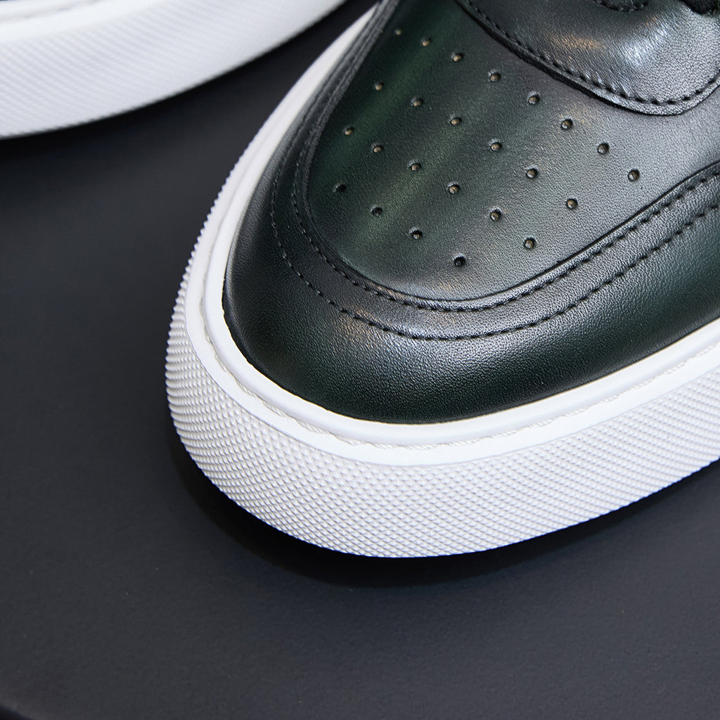 Close-up of dark green leather toe with perforations and lace-up panel, white midsole.