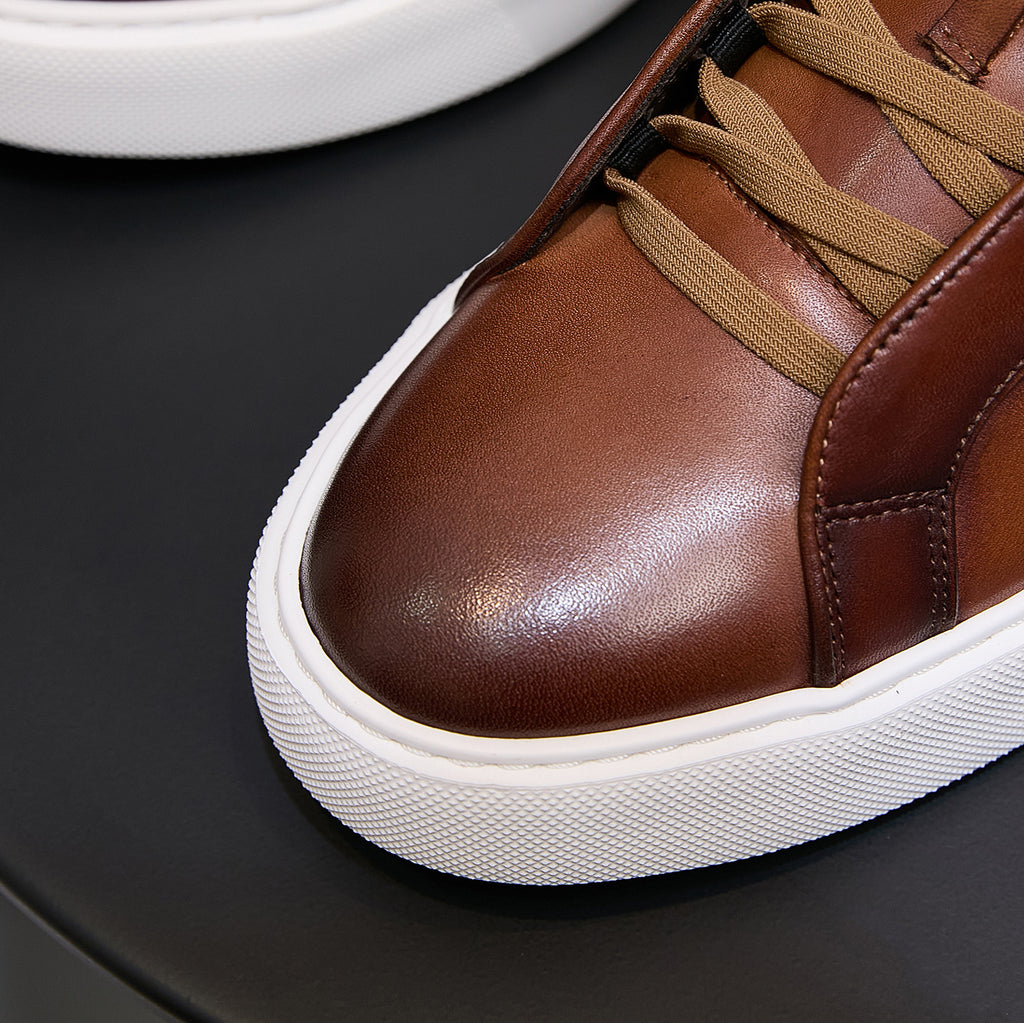 Brown leather sneaker toe with tan laces and white textured sidewall sole