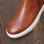 Brown leather slip-on style dress boot with pointed toe and white rubber sole