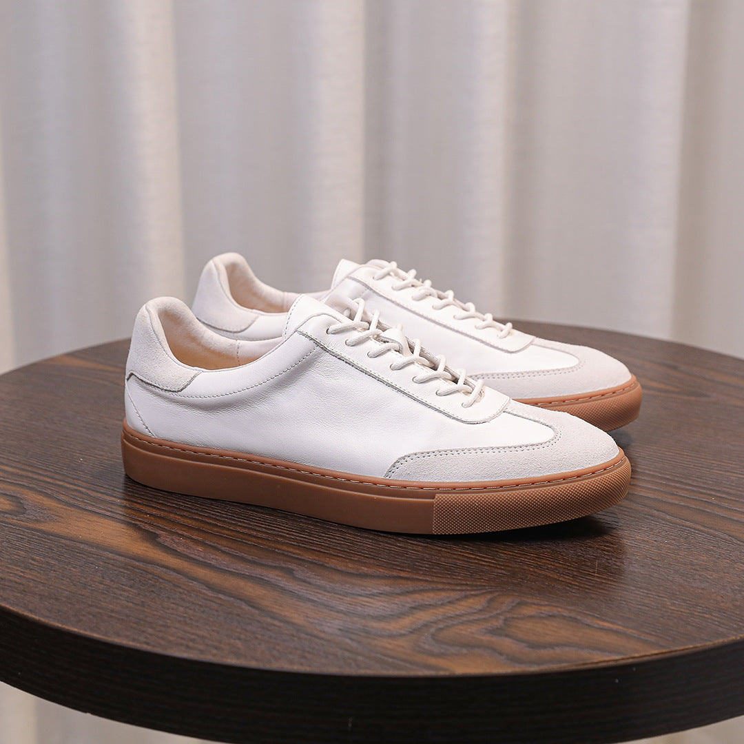 White leather lace-up sneakers with tan sole, side profile on table
