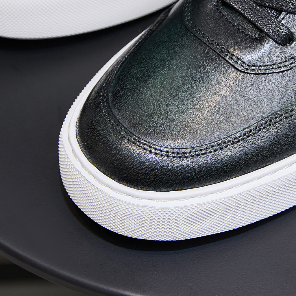 Close-up of men's dark green leather sneaker toe and stitched trim with black laces