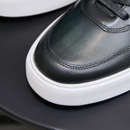 Close-up of men's dark green leather sneaker toe and stitched trim with black laces