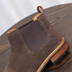 Dark brown suede pointed-toe Chelsea boot with elastic side panels and rubber sole.