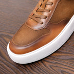 Brown leather sneaker upper detail with laces, stitching, and white sole edge