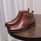 Brown leather pointed-toe ankle dress boots with side zipper and stitched sole.