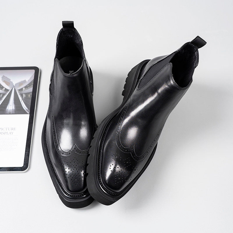 Black leather Chelsea dress boots with elastic gore, brogue-style perforations, angled view