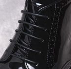 Men's black dress boots close-up: lace-up front and glossy leather paneling