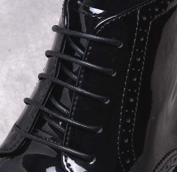 Men's black dress boots close-up: lace-up front and glossy leather paneling