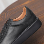Men's black leather sneaker close-up, smooth side panel and lace eyelets