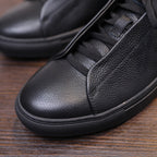 Men's black genuine leather sneaker upper close-up with laces and rubber toe cap