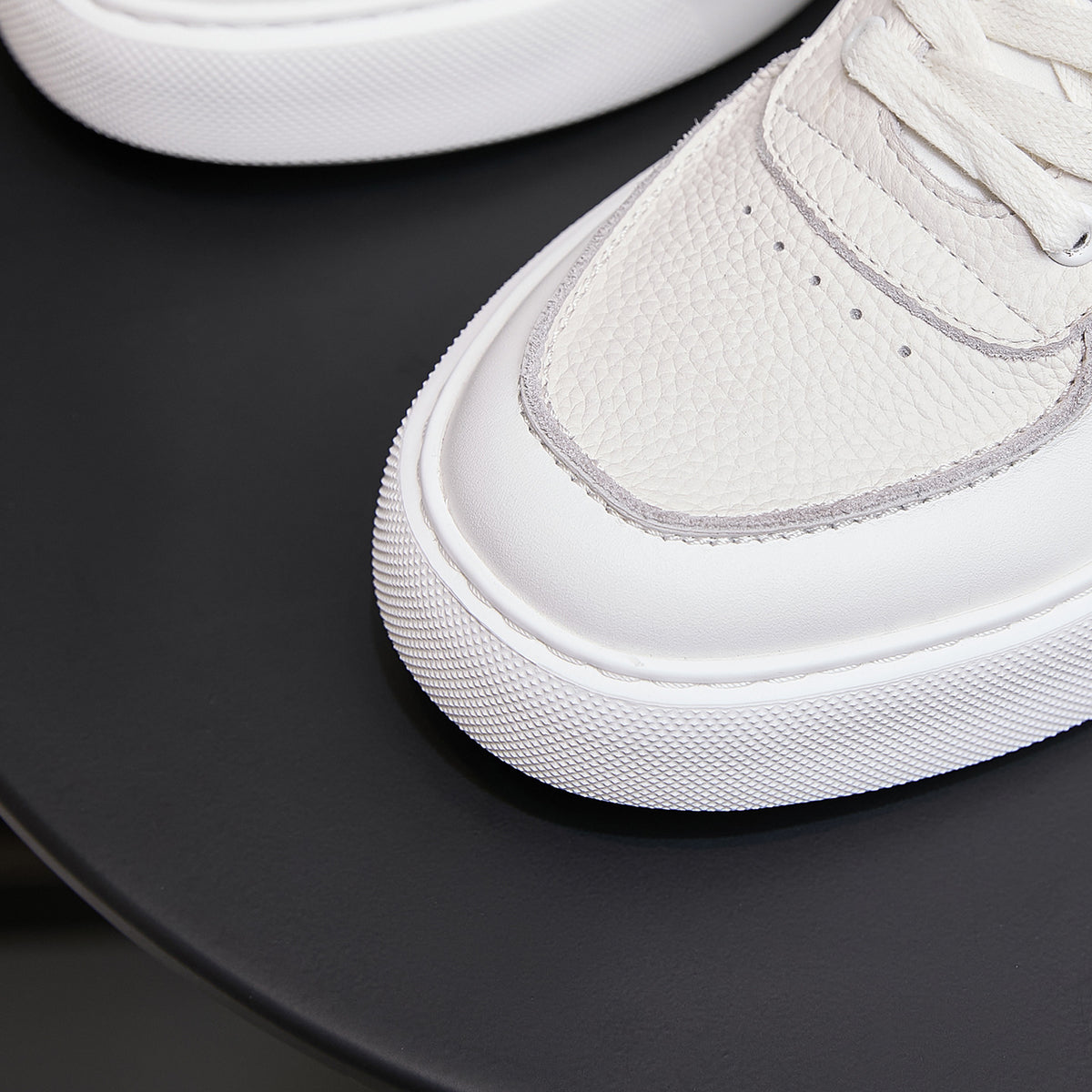 White leather sneaker toe with textured upper and stitched trim