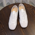 Pair of men's white leather sneakers with lace-up design and rounded toe