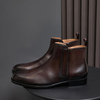 Pointed-toe leather side-zip dress boot in dark brown, front view on round stand