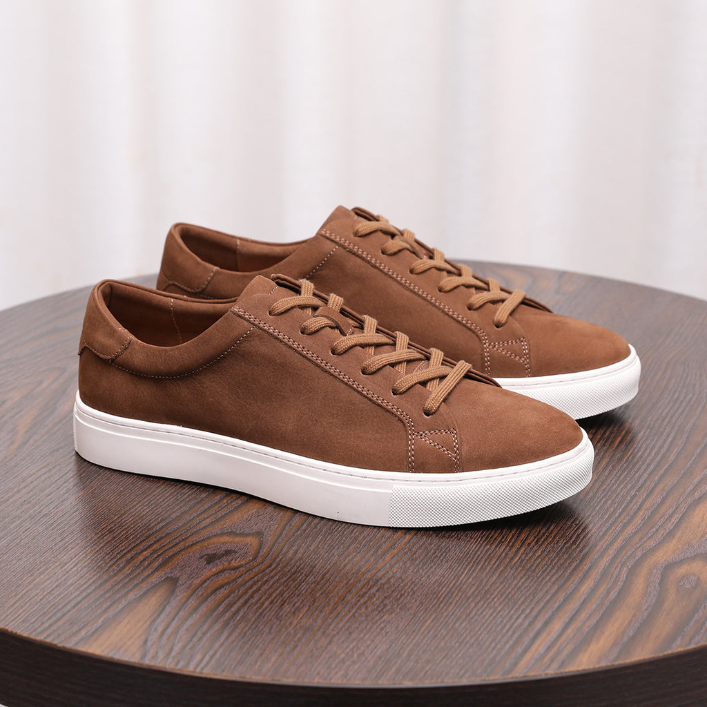 Tan brown suede leather sneakers with lace-up front and white rubber sole.