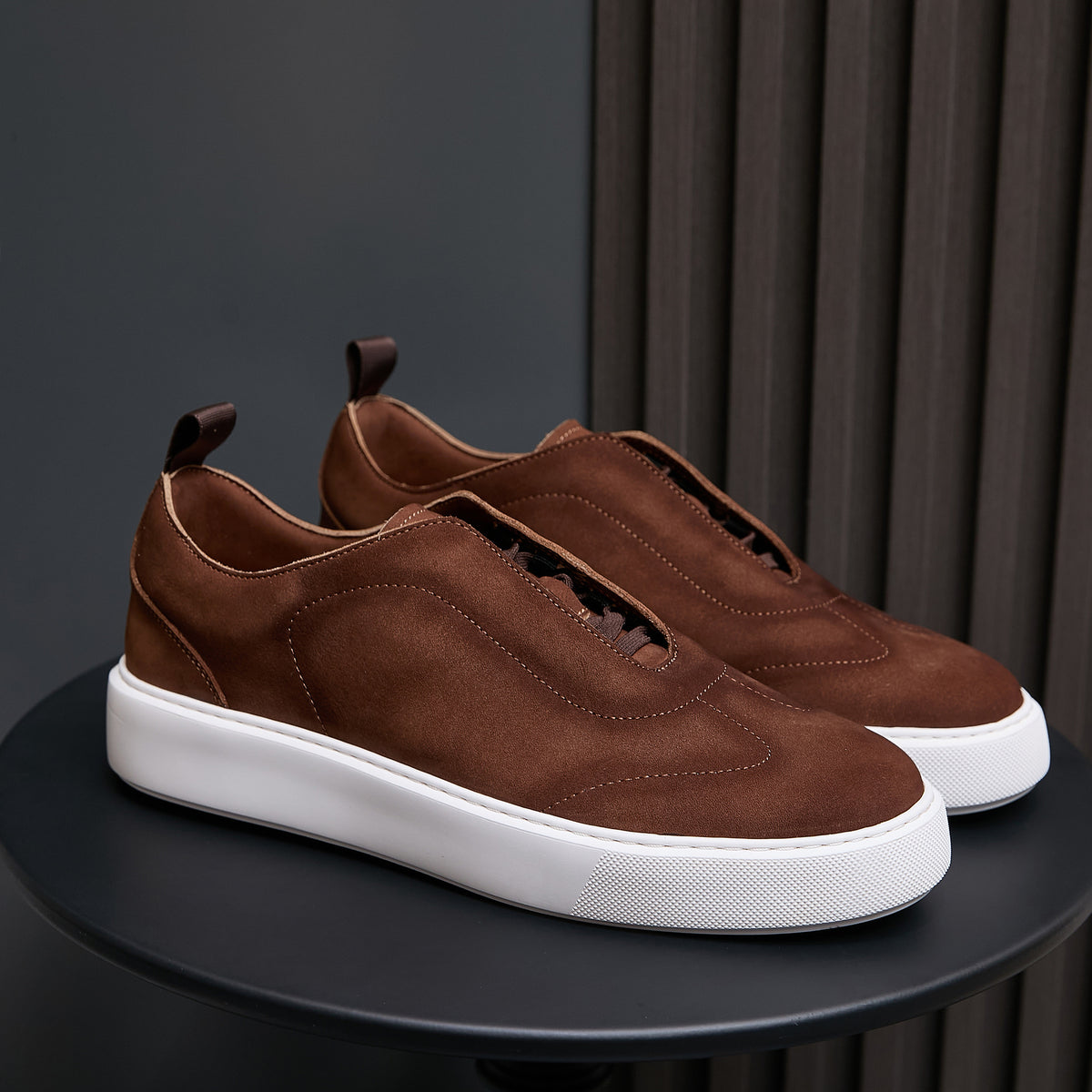Brown leather sneakers with lace-up front and white rubber sole on display