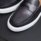 Close-up of black leather slip-on sneakers with moccasin stitching and white platform sole